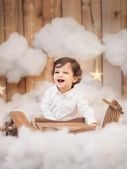 Pure, unfiltered joy. This little pilot's laughter is everything. For his first birthday photoshoot, we created a magical sky with a wooden airplane and fluffy clouds, making his milestone celebration truly unforgettable.