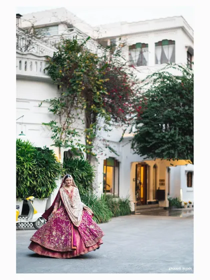 A beautiful bridal twirl. The bride's magnificent magenta lehenga is on full display against the classic architecture of the venue.