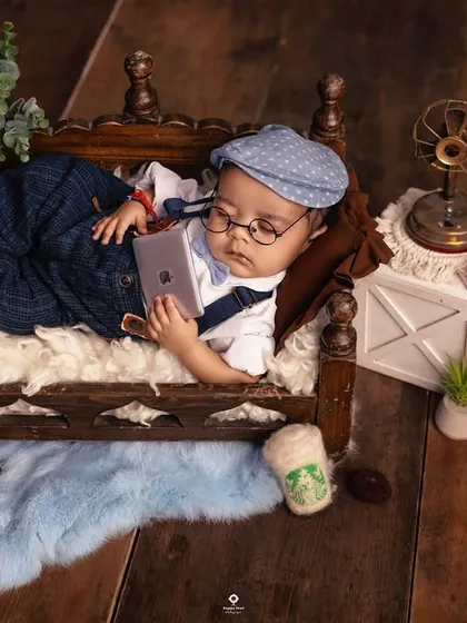 A modern take on a newborn portrait. This little one is styled like a tiny professional, relaxing on a mini-daybed with a miniature laptop and a cup of coffee.