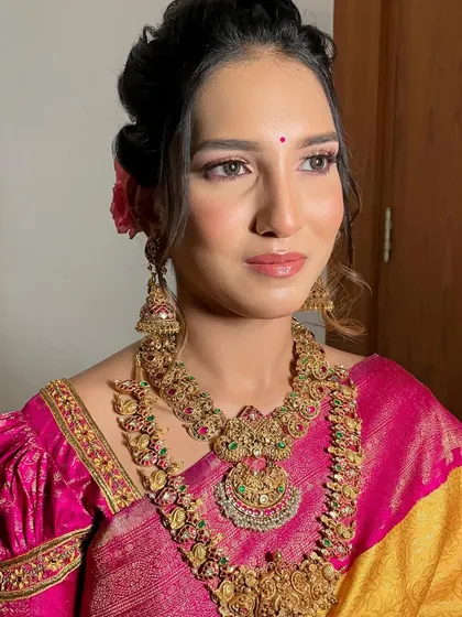 This bride's soft glam look is perfectly captured here. The focus is on her luminous skin and the beautiful harmony between her pink-toned makeup and the vibrant colors of her silk saree.