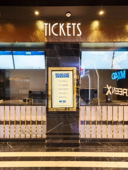 The ticket counter at INOX Jalosa is designed to be both functional and glamorous. The use of black marble with gold veining, combined with elegant brass detailing, elevates a simple transaction point into a part of the overall luxury experience.