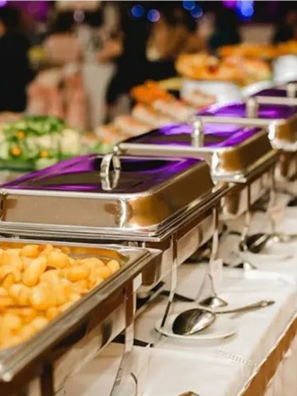 Food should be a feast for the eyes too. This is a snapshot of an elegant buffet arrangement, showcasing a variety of dishes in professional chafing dishes, ensuring the food stays warm and is presented beautifully for a large gathering.