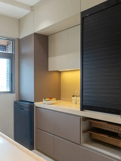 This design in Vile Parle includes an appliance garage with a black rolling shutter to keep the countertop clutter-free. Below, open shelves with wicker baskets provide easy-to-access, breathable storage for vegetables.