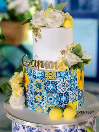 The stunning two-tiered cake, with the bottom tier wrapped in a Delft Blue tile pattern and topped with fresh flowers.