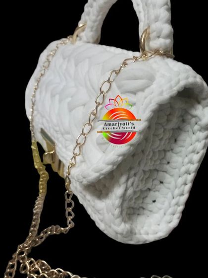A side profile of the white handbag, displaying its depth and the sturdy construction of the crocheted panels.