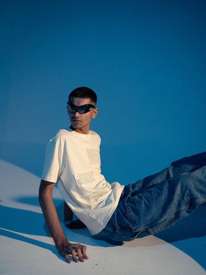 A futuristic, cool-toned shoot for Varsey Clothing. The blue background and the model's sleek sunglasses create a modern, almost sci-fi aesthetic.