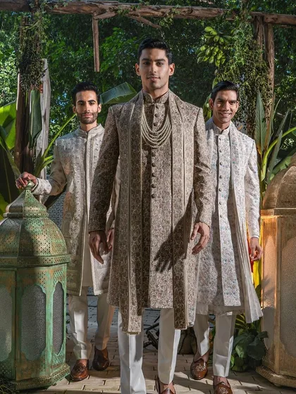 The groom takes center stage, his presence commanding and regal in a layered, patterned sherwani. This image captures the confidence that comes from wearing a perfectly tailored, bespoke garment.