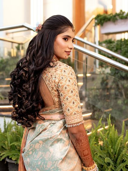 A bride in a pastel blue and peach saree. The back of her blouse features a beautiful cut-out design and heavy embroidery.