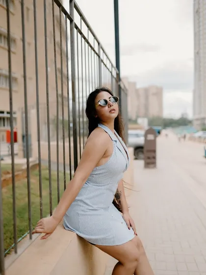 A stylish portrait of a model sitting on a ledge in the city. Her pose and the urban background create a chic and contemporary fashion shot.