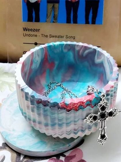 This is our Aurora bowl, a custom piece we made for a client. The swirling blend of colors was inspired by the northern lights. It's shown here being used as a jewelry holder.