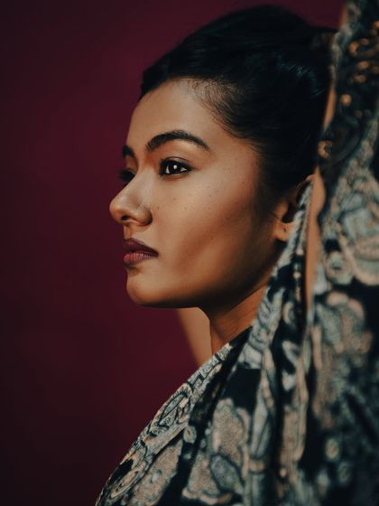 A classic profile shot that highlights the model's features and the elegant updo. The fabric in the foreground adds a layer of depth and mystery to the composition. This is a timeless and graceful beauty portrait.