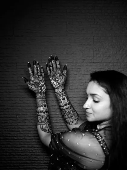 A serene black and white profile shot of the bride admiring her henna-adorned hands.