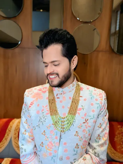 This groom's pastel floral sherwani is paired with a stunning multi-layered green bead necklace, adding a touch of modern royalty.