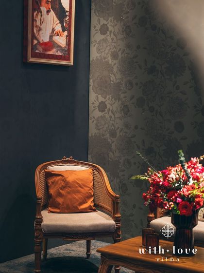 A detail shot of a seating corner, where the light catches the texture of the cane chair and the rich colors of the floral arrangement. Every element is carefully considered to contribute to the overall mood.