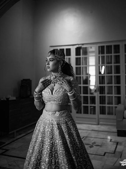 A candid black and white shot of the bride getting ready, adjusting her necklace in a moment of quiet anticipation.