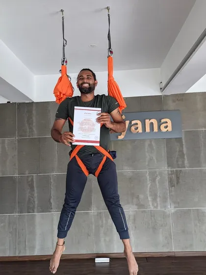 A joyful graduate hangs in his harness, certificate in hand, after completing the aerial TTC.