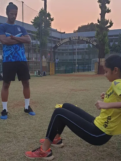 A coach supervises an athlete performing a hip thrust, a key exercise for strengthening the glutes which are critical for running and jumping power.