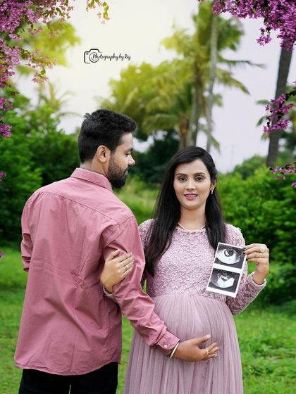A lovely couple's portrait showing them holding their baby's ultrasound pictures. The mother-to-be is wearing a beautiful pink lace gown.