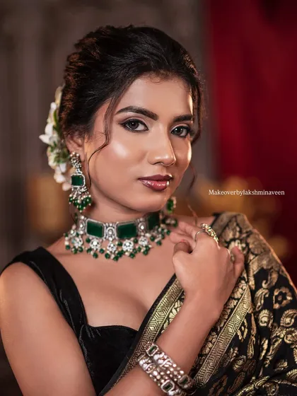 A portrait shot focusing on the makeup and jewelry for the classic black saree look.