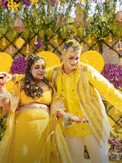 The couple dances amidst a shower of flower petals at their Haldi function. We aim to create an atmosphere of pure joy and celebration.