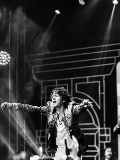 A black and white shot of a performer on stage, capturing the raw energy and passion of a live musical performance at a sangeet.