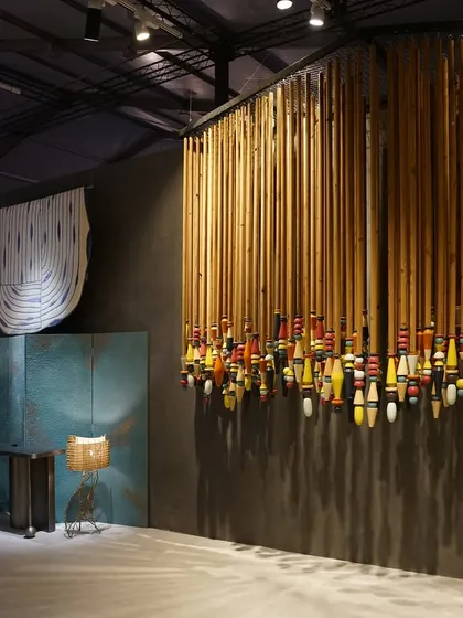A curated view of the 'India Everywhere' space, showing a large installation of colorful lacquered wood objects from Channapatna. This piece stands in dialogue with the woven copper panels, representing India's diverse craft traditions.