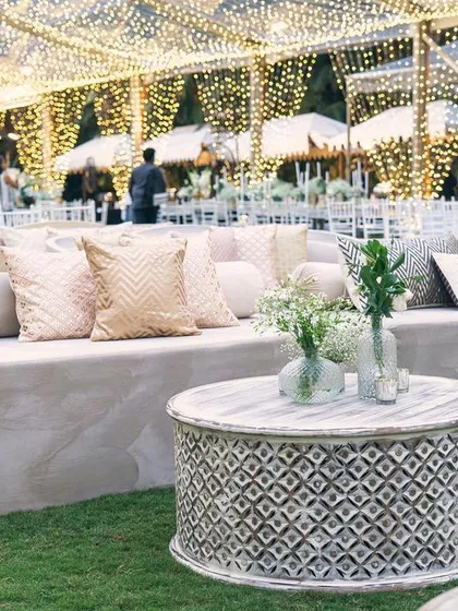 A comfortable and stylish lounge area at the sangeet. The combination of plush velvet seating and intricately carved tables provides a perfect space for guests to mingle.