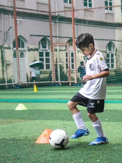 A young player practices dribbling with his eyes up, a critical skill for developing game awareness that we emphasize in our coaching.