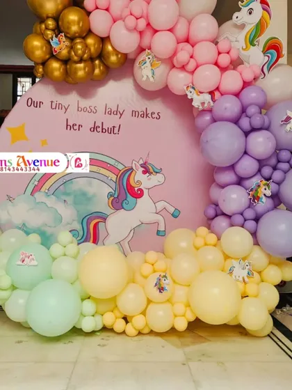 A close-up of the unicorn backdrop and the multi-colored balloon garland, featuring shades of pink, purple, yellow, and mint green.