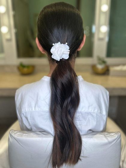 Spring into style with a chic ponytail, adorned with a white floral accessory. Our expert stylists can craft the perfect look for any season.