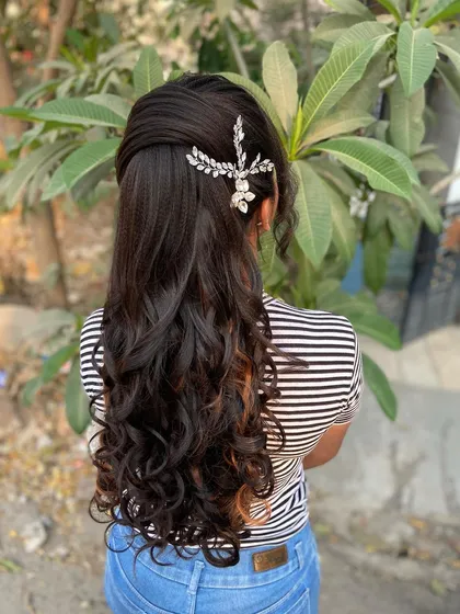An elegant curly ponytail adorned with a sparkling hair accessory. This is a perfect example of a modern reception hairstyle that is both stylish and secure.
