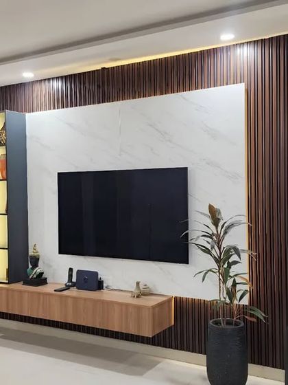 This view shows how the TV unit's warm white accent lights create the perfect ambiance for movie nights. The floating console and vertical display cabinet offer a mix of open and closed storage.