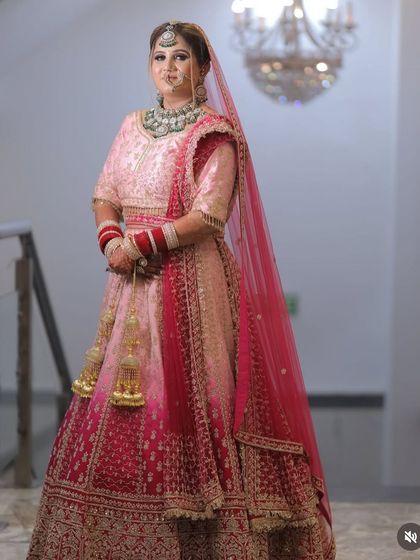 This bride chose a beautiful ombre lehenga fading from light pink to deep magenta. Her makeup is soft and glowing, with a focus on a flawless, dewy complexion.