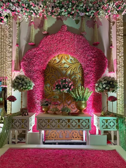 An opulent photo corner, featuring a statement arch of pink flowers, a gold-patterned backdrop, and a floor of fresh petals. It's designed to impress at every glance. 🌸