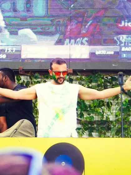 Me on the mic, arms outstretched, soaking in the energy of the Holi crowd. These are the moments I live for.