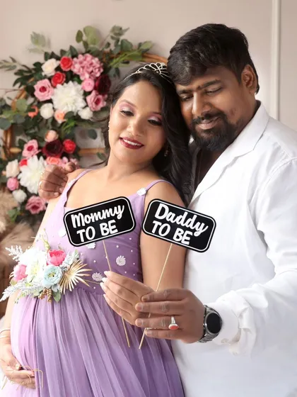 A fun and celebratory portrait of a couple with 'Mommy to be' and 'Daddy to be' props in our boho studio.
