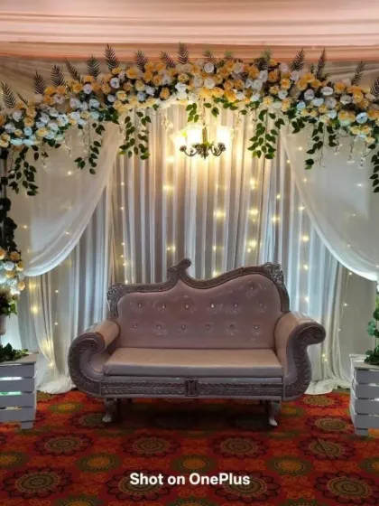 An engagement stage with a floral arch made of yellow and white roses. The backdrop of white drapes and fairy lights creates a dreamy and romantic atmosphere.