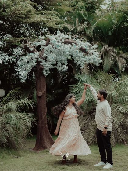 The couple sharing a dance under a beautiful, whimsical tree in a lush garden.