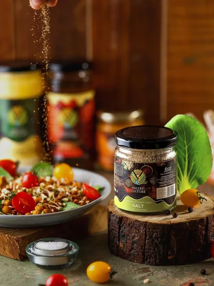 A dynamic shot of Valley Culture's flavored salt being sprinkled over a salad. This action shot demonstrates the product's use in a delicious and healthy context, making it instantly relatable.