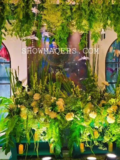 A beautiful backdrop featuring faux windows with parrot motifs, surrounded by an abundance of fresh flowers and greenery.