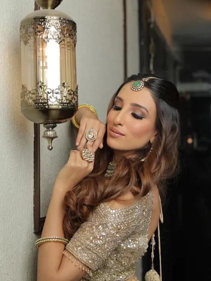 Majestic and ethereal. This look combines a shimmering gold outfit with soft, smoky eyes and a beautiful emerald maang tikka for a touch of color.