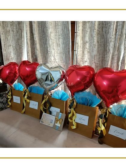 A row of surprise gift bags decorated with balloons, ready to make someone's anniversary extra special.