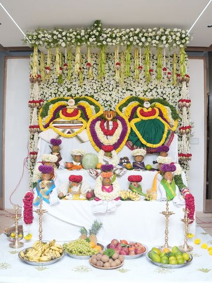 A traditional setup for a housewarming ceremony, with deities adorned with beautiful flower garlands. The space is filled with fruits and offerings, creating a sacred and blessed atmosphere for the new beginning.