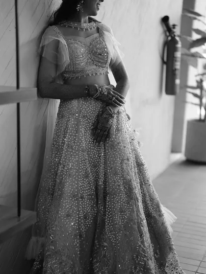 A timeless black and white portrait of the bride. This photo highlights the texture and detail of her embellished lehenga, creating a classic and elegant look.