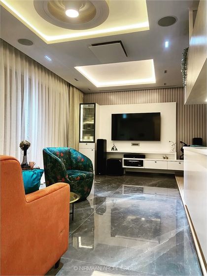 Another view of the smart living room at Bhagwati Greens. The combination of vibrant armchairs, marble flooring, and automated lighting creates a luxurious and technologically advanced space.