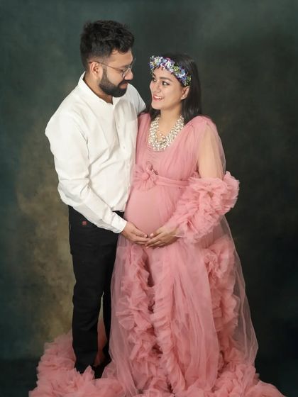 Looking at each other with so much love. The flowing pink gown adds a touch of romance and elegance to this classic studio maternity portrait.