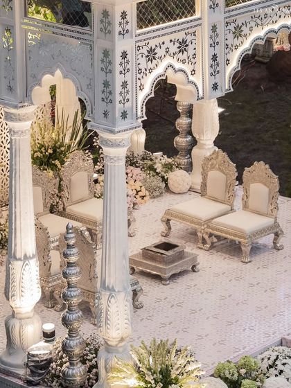 An elevated view of the mandap seating, showcasing the pristine white tiled floor and ornate silver chairs for the couple. The design blends traditional Indian wedding motifs with a clean, modern aesthetic.