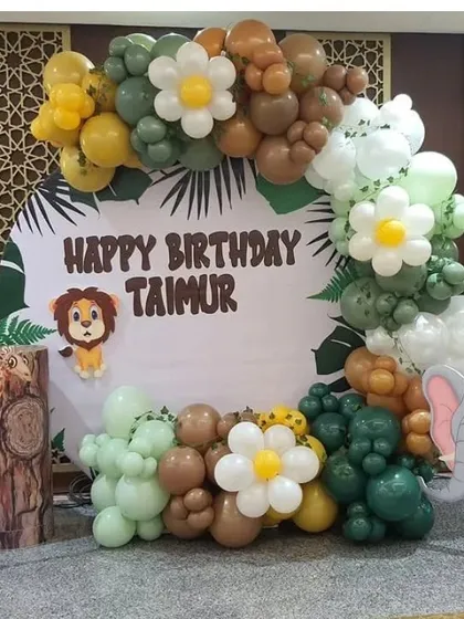 A jungle-themed birthday party with a custom backdrop and character cutouts of a lion and elephant.
