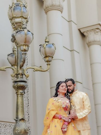 A low-angle shot of a couple posing in front of grand pillars, creating a majestic feel for their daytime event.