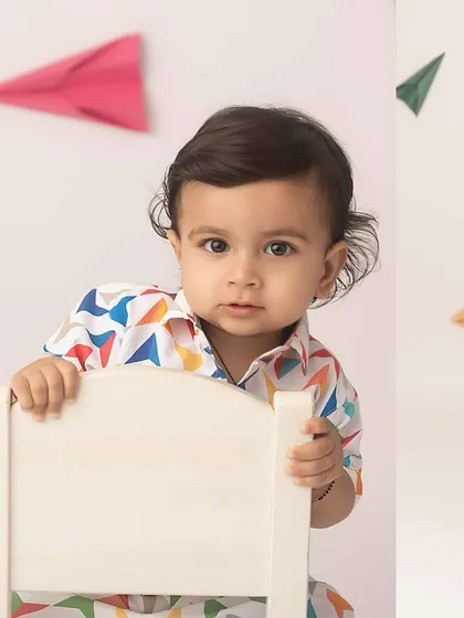 A sweet portrait peeking over the chair, surrounded by paper planes.